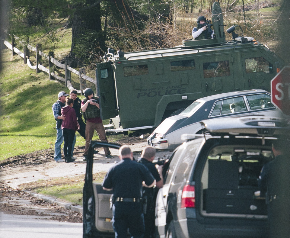 Police with an armored vehicle surround a woman after she left a house on Elizabeth Road in Portland, where a shooting on Friday left one person wounded and another in custody.