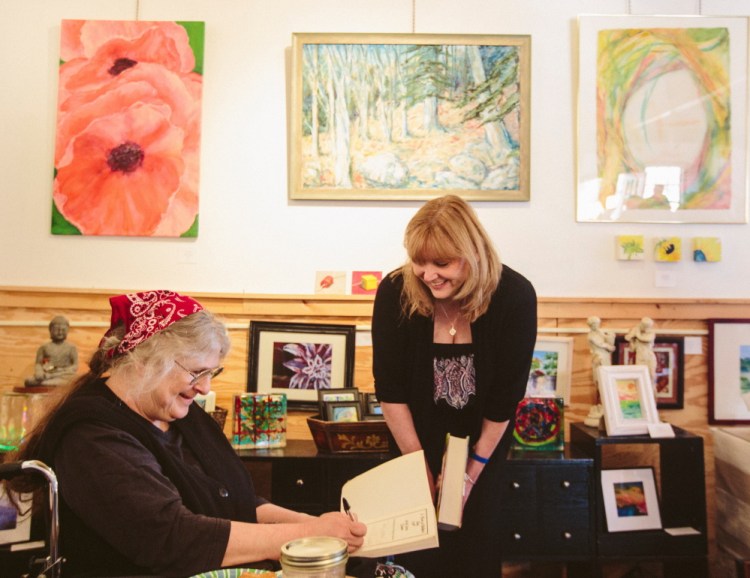 Carolyn Chute signs a book Saturday for Carmel Curran Blanchette of Framingham, Mass., at the Blackbird Gallery and Studio in North Berwick.