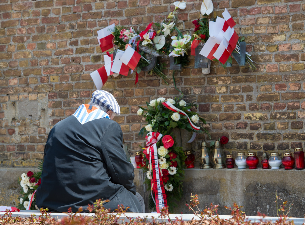 A Nazi concentration camp survivor from Poland sits at the Wall of Nations in front of the word ‘Polen’ (Poland), adorned with flowers and flags, at the Ravensbrueck memorial site during ceremonies marking  the 70th anniversary of the camp’s liberation in Fuerstenberg, Germany, on Sunday.