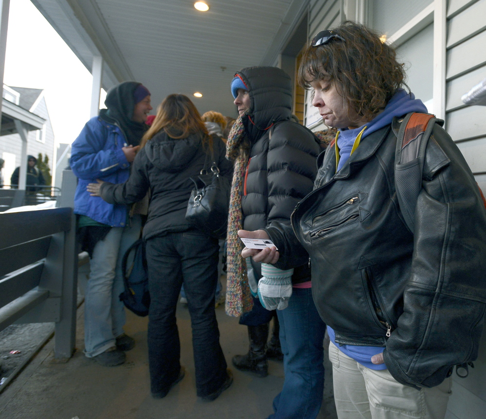 Lori Godin holds her shelter ID card March 12 as she waits in line to spend the night at the Oxford Street Shelter in Portland. She is working full time at a South Portland hotel and trying to build up some savings.