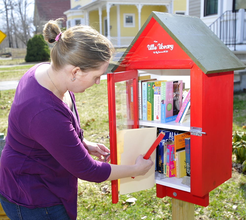 Bethany Hundt looks at the damage to the Little Free Library, which her father built, in her front yard on Summit Street in South Portland.