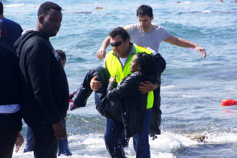 A man rescues a migrant from the Aegean Sea on Monday. Greek authorities said at least three people have died, including a child, after a wooden boat ran aground.