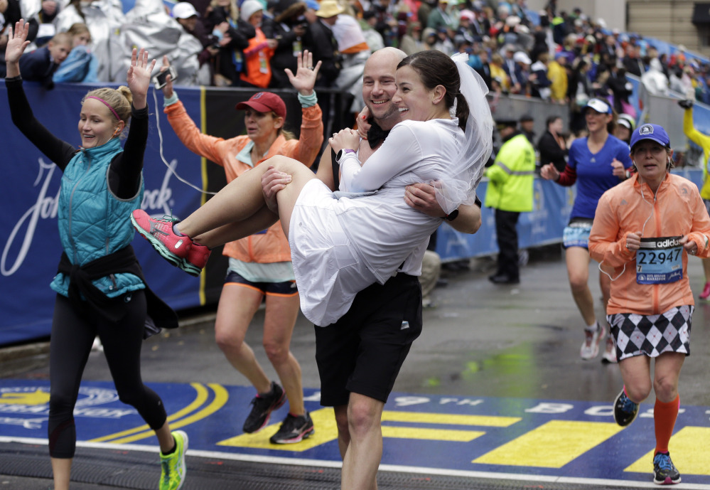 Ross Cockerham carries Ansley Proctor over the finish line after they ran the Boston Marathon on Monday. The couple from Columbia, Md., are set to be married Saturday.