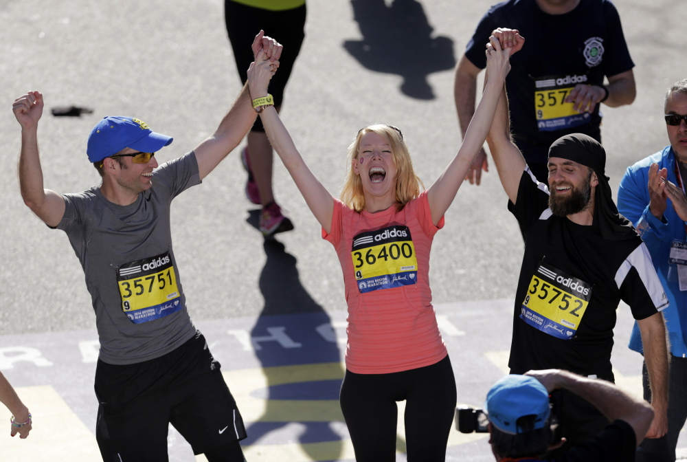 Timothy Haslet, left, and David Haslet, right celebrate with their sister Adrianne Haslet-Davis as she crosses the finish line of the 118th Boston Marathon Monday, April 21, 2014 in Boston. Haslet-Davis, a professional dancer, lost her lower left leg at last year's marathon when one of two bombs exploded as she watched runners near the finish line. (AP Photo/Charles Krupa)