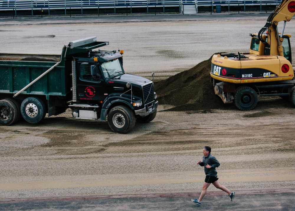 Paul Pietropaoli runs the track at Fitzpatrick Stadium while Northeast Turf of South Portland works on installing a new  artificial field. The $1 million project follows a bleacher replacement three years ago and a lighting overhaul in 2013.