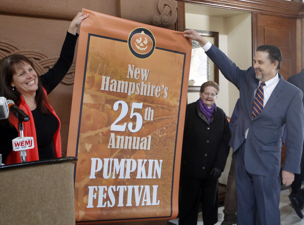 Ed Engler, right, the mayor of Laconia, N.H., helps unroll a poster Friday announcing the city as the new host of the annual Pumpkin Festival. Held in Keene since 1991, the family-friendly event was marred by arrests last year, many of them college students.