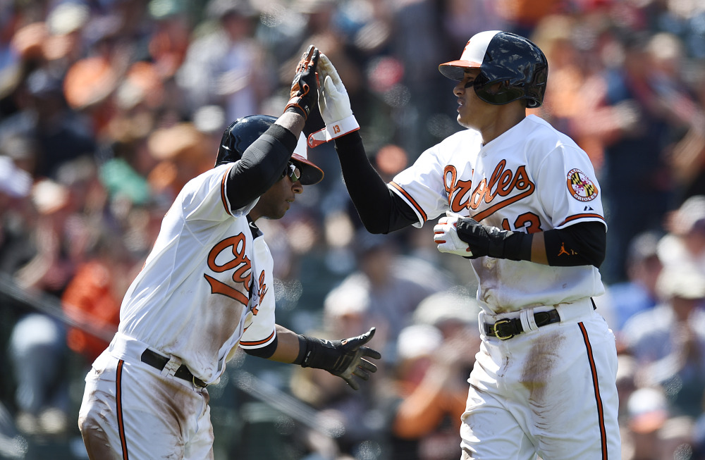 Baltimore Orioles Manny Machado, right, and Rey Navarro celebrate after scoring on a Delmon Young single against Boston Red Sox in the fourth inning  Sunday in Baltimore.