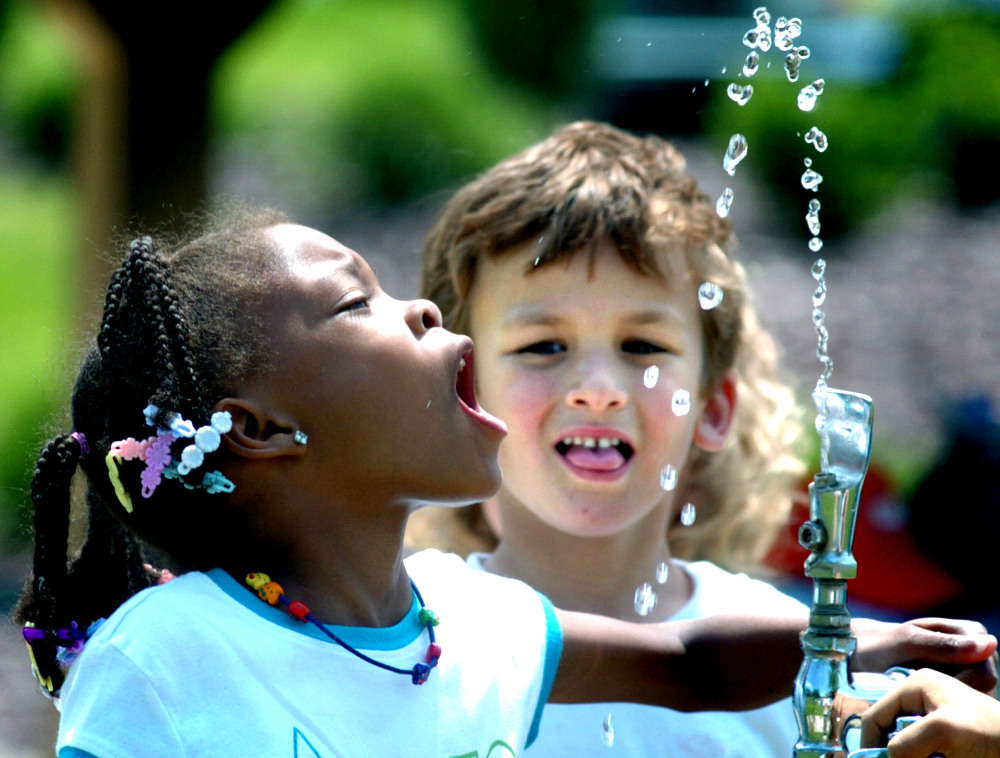 Tianna Swisher tries to drink from the water fountain at Montour Preserve near Washingtonville, Pa. Fluoride in drinking water, credited with dramatically cutting cavities and tooth decay, has been tied to white splotches on children’s teeth.