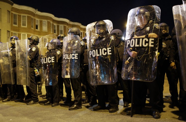 Police stand in formation as a curfew approaches Tuesday night in Baltimore, a day after rioting that followed Freddie Gray’s funeral.