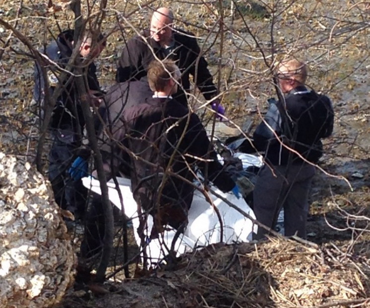 Police examine the body that was found Tuesday afternoon on the shore of the Fore River in South Portland.
