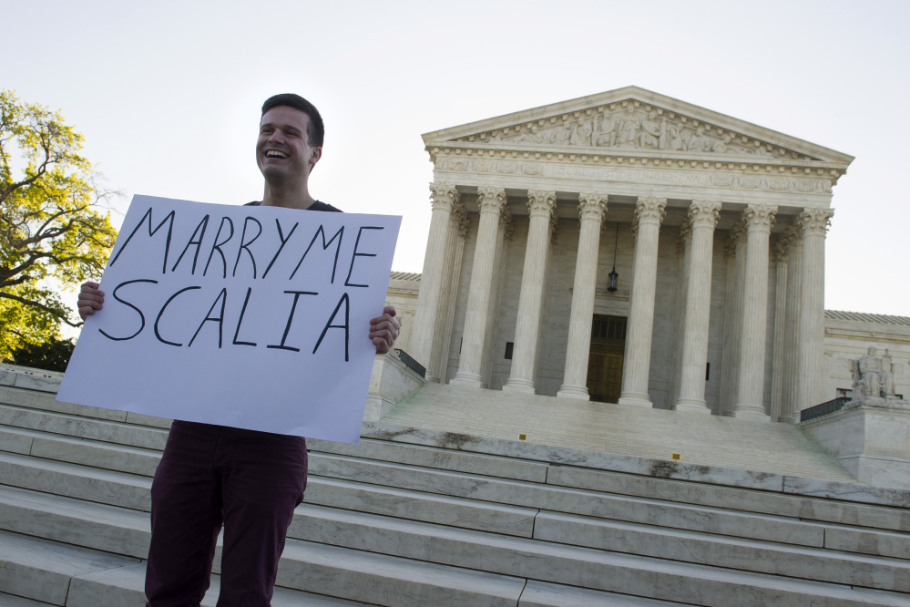 Ryan Aquilina, 24, of Washington holds a sign in front of the Supreme Court in Washington on Tuesday, as justices were set to hear historic arguments in cases that could make same-sex marriage the law of the land.