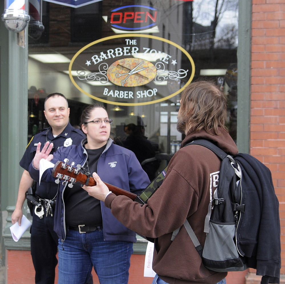 Augusta Police Detective Tori Tracy and Officer Jesse Brann speak with a man Wednesday playing guitar on Water Street while canvassing. Law enforcement officers were notifying people of a larger police presence planned in crime “hot spots” while soliciting information on how to combat crime.