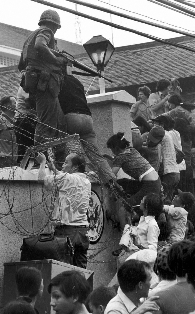On April 29, 1975, people scale the 14-foot wall of the U.S. embassy in Saigon, trying to reach evacuation helicopters, as the last of the Americans depart from Vietnam.
