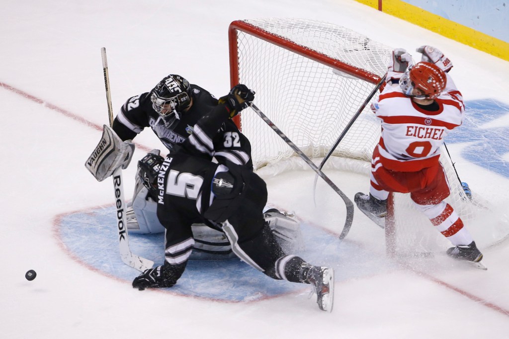 Jon Gillies of South Portland, the goalie for Providence College, knocks away a shot by Jack Eichel of Boston University – who won the Hobey Baker Award as the nation’s top college hockey player – while colliding with defenseman Kyle McKenzie during Providence’s 4-3 victory Saturday night in the NCAA championship game.
