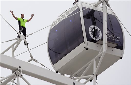 Daredevil performer Nik Wallenda waves to a crowd below after he walked untethered along the rim of the Orlando Eye, the city's new, 400-foot observation wheel, Wednesday in Orlando, Fla.