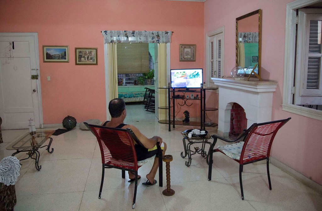 A homeowner sits in the living room of the home where he rents rooms in Havana. The Associated Press