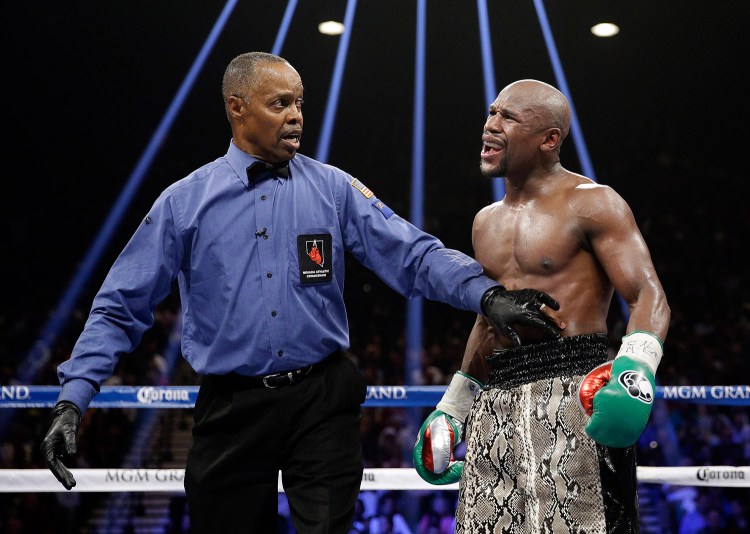 Boxer Floyd Mayweather, shown speaking to referee Kenny Bayless, has proved a smart businessman by signing for a fight that will earn him $180 million or more.