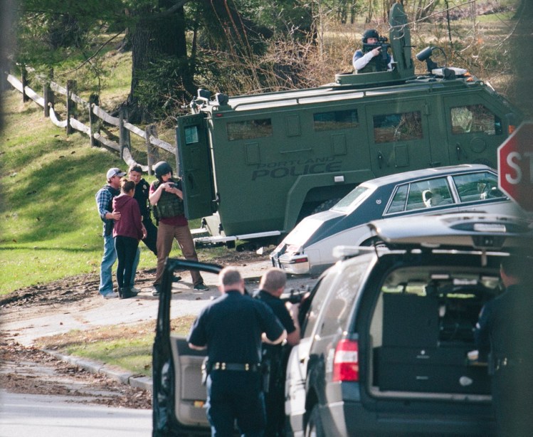 A woman is accompanied by Portland police near an armored vehicle after she left a house on Elizabeth Road where a shooting left one person seriously wounded and another in custody in Portland on Friday.