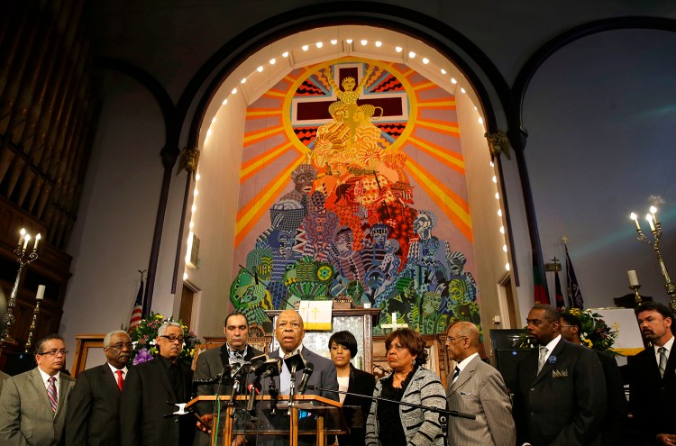 Rep. Elijah Cummings, D-Md., center, speaks in front of faith and community leaders at a news conference calling for peace in response to a Freddie Gray protest that turned violent, Sunday. The Associated Press
