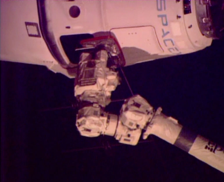 A robotic arm from the space station connects with the SpaceX Dragon freighter with its delivery of groceries, equipment and experiments.