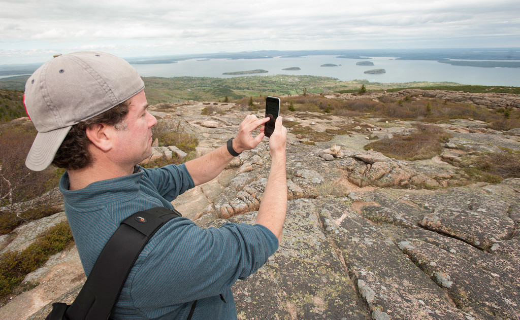 Kerry Gallivan demonstrates his Chimani app while standing atop Cadillac Mountain in Acadia National Park this month. Chimani, launched in 2010, is developing a series of free mobile apps for national parks and other outdoor attractions that combine the benefits of a map, guide book and activity planner into one digital package. 