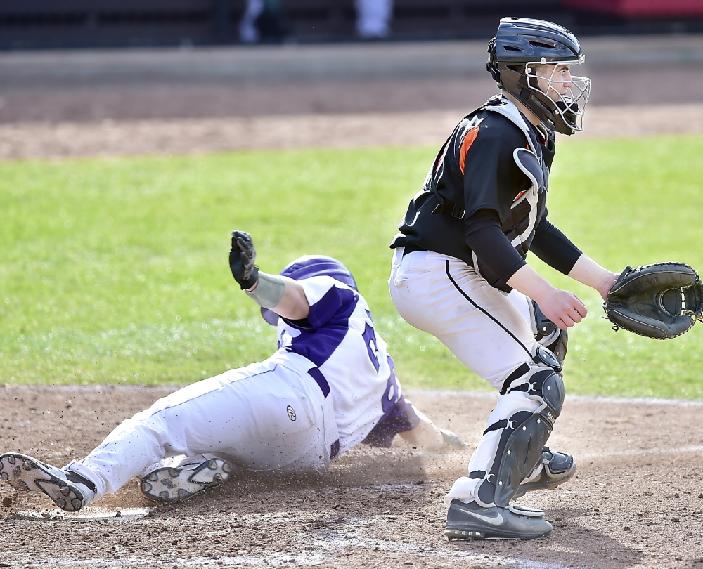 Jake Latini slides home safely to score for Deering as Biddeford catcher Joe Curit waits for a late throw from right field Thursday during Deering’s 6-5 victory at Hadlock Field.