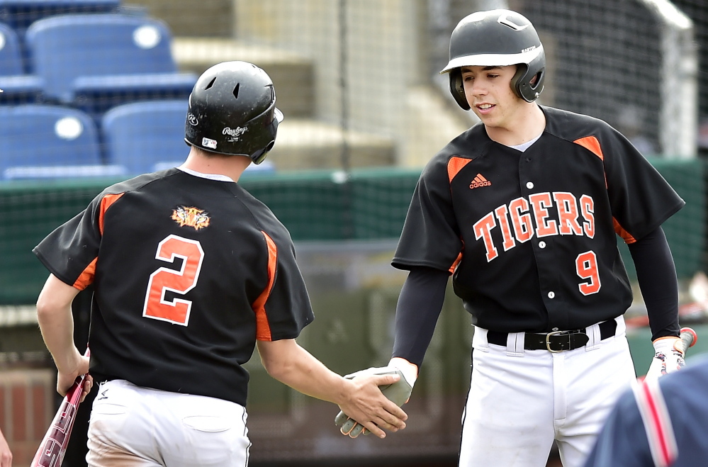 Dominick Day of Biddeford, left, is welcomed by Nick Conley after scoring against Deering in their SMAA game. Deering scored three runs in the seventh inning to walk off with the victory.
