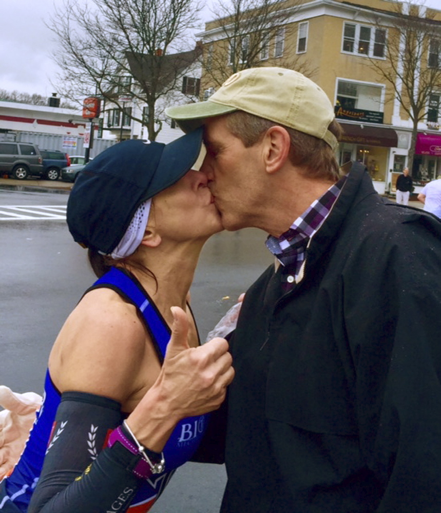 In this photo provided by Paige Tatge, her mother, Barbara Tatge, kisses an unknown spectator in Wellesley, Mass., during the Boston Marathon on April 20. Tatge made good on a dare by her daughter that she kiss a man as she ran the race. Now, they would like to know who she kissed.