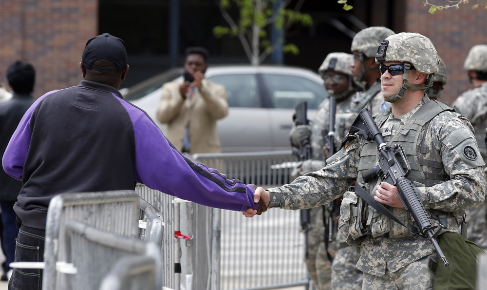 A man shakes hands with a National Guard soldier outside Baltimore City Hall on Friday. State’s Attorney Marilyn Mosby announced criminal charges Friday against all six officers suspended after Freddie Gray suffered a fatal spinal injury in police custody. Mosby brought the stiffest charge, second-degree murder, against the driver of the police van involved.