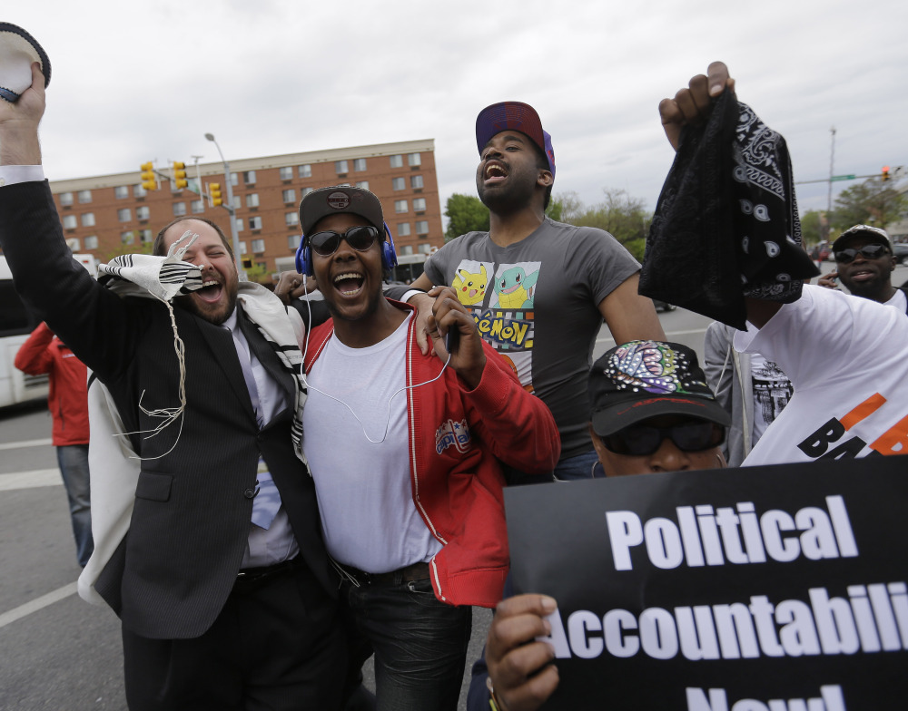 Rabbi Yerachmiel Shapiro, left, and other citizens celebrate Friday after State’s Attorney Marilyn Mosby announced criminal charges against the six officers involved in the Freddie Gray case. She urged protesters to “channel your energy peacefully.”