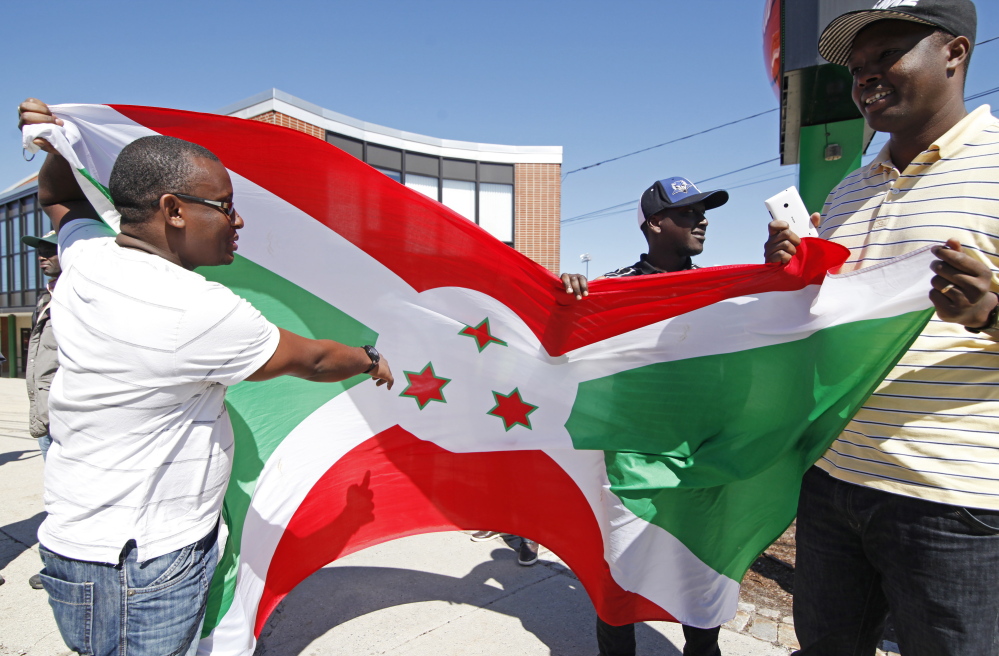PORTLAND, ME - MAY 2: Yves Florent, Richard Irakoze and Euphrem Manirakiza, all of Lewiston hold the Burundi flag and discuss the three stars reprenting the three Burundi cultural groups  before they and other immigrants from Burundi march from the Portland Expo to Monument Square Saturday, May 2, 2015 to protest the Burundi president who is seeking a third term which goes against the constitution. (Photo by Jill Brady/Staff Photographer)