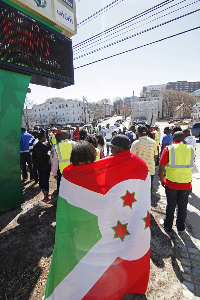 A couple embrace under a Burundi flag as Immigrants from Burundi gather to march from the Portland Expo to Monument Square Saturday. Jill Brady/Staff Photographer