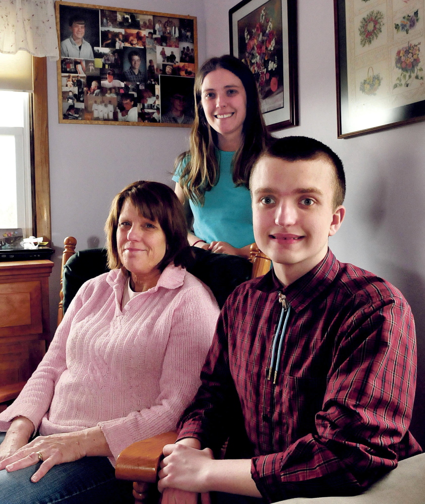 Yvonne Batson with her children Corina and Nathanael at home in Fairfield. Behind them are photographs of Yvonne’s son Brendan, who died in 2001. Nathanael, who is legally blind because of a genetic disorder the Batsons share, is close to achieving the rank of Eagle Scout.