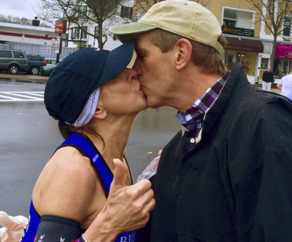 Boston Marathon runner Barbara Tatge, left, kisses an unknown spectator in Wellesley, Mass. After a search, Tatge received a good-humored response from the man’s wife.