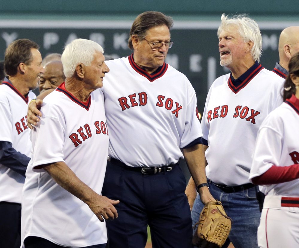 Former Red Sox catcher Carlton Fisk, center, puts his arm around Carl Yastrzemski while Bill Lee, right, chats with them during pre-game ceremonies Tuesday night at Fenway Park honoring the 1975 Red Sox team, which won the American League pennant.