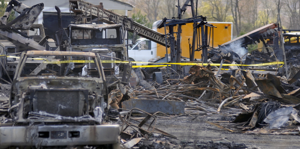 Charred vehicles sit amid the debris of the building that burned Wednesday in Monmouth. One employee of AD Electric was hurt in the fire, and OSHA officials are investigating to determine whether the injured employee or the company violated federal safety standards.