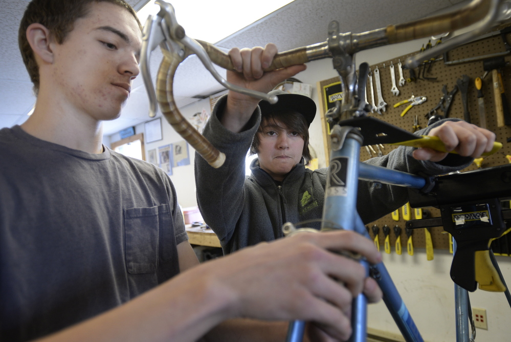 Westbrook High School seniors Tyler Eastman, left, and Morgan Mulkern work together to take a bicycle apart.