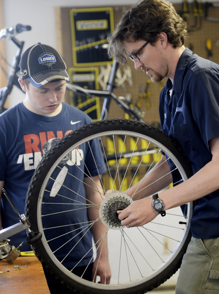 Sophomore Joseph Gately and teacher Shannon Belt work together on a tire.