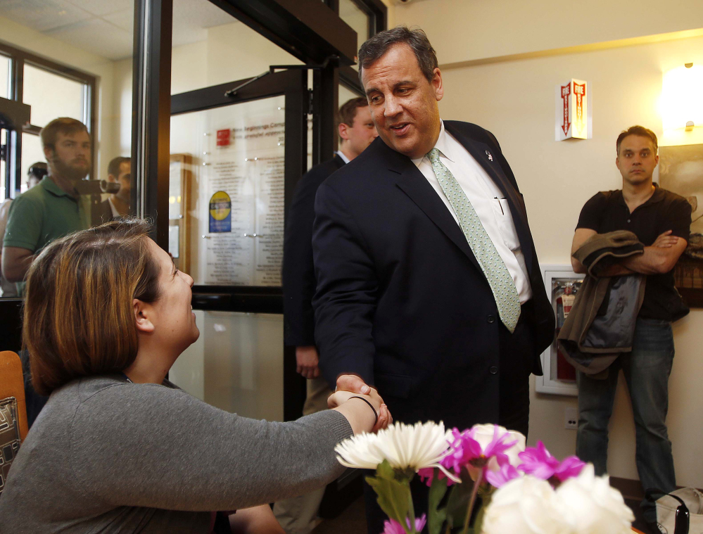 Stephanie Rhodes, left, shakes hands with New Jersey Gov. Chris Christie as he arrives for a roundtable discussion Thursday at the Farnum Center in Manchester, N.H.