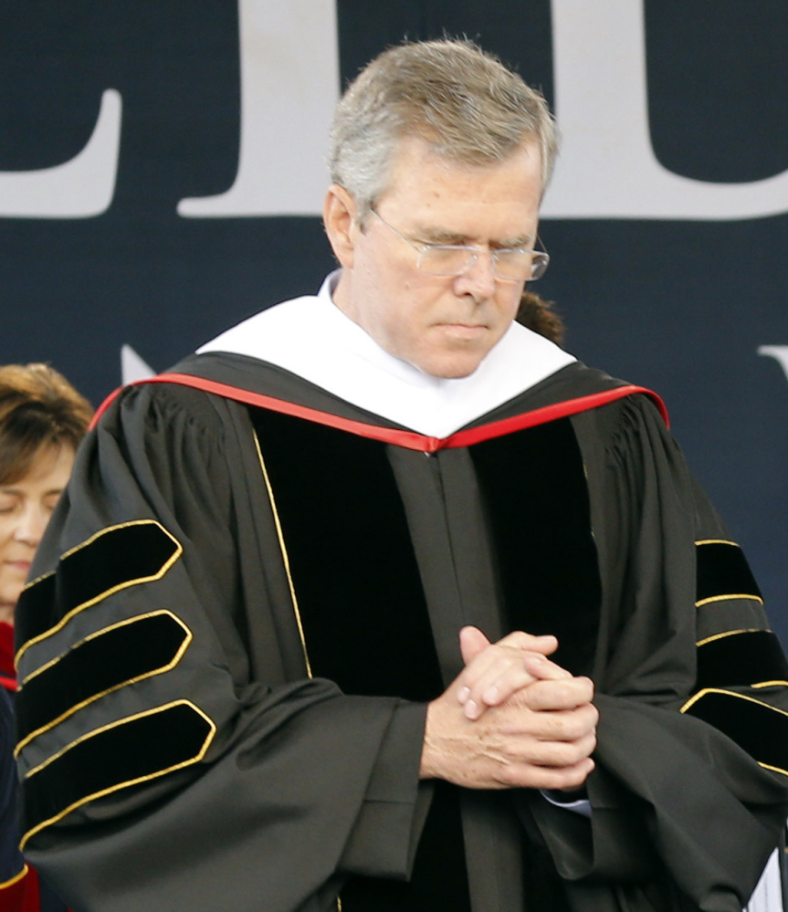 Jeb Bush bows his head in prayer during  commencement at Liberty University on Saturday.