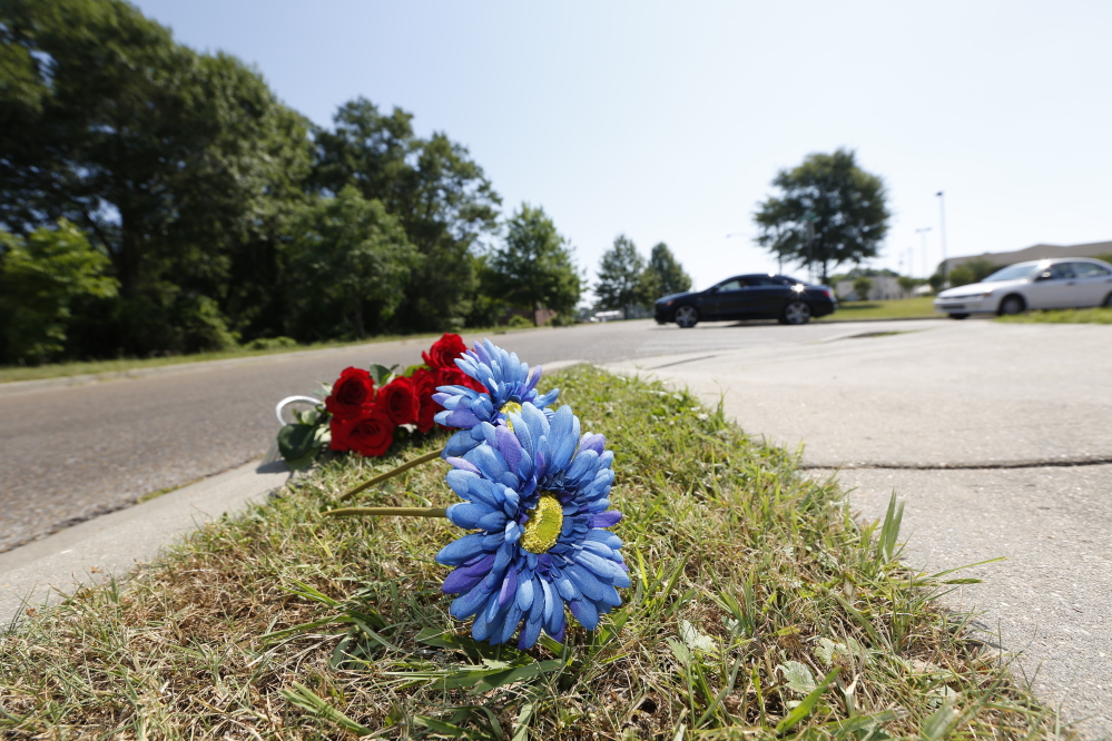 A bouquet of Mother’s Day roses and two silk flowers are placed along the sidewalk on Sunday near the site where two Hattiesburg, Miss., police officers were fatally shot during a traffic stop the night before, in Hattiesburg.