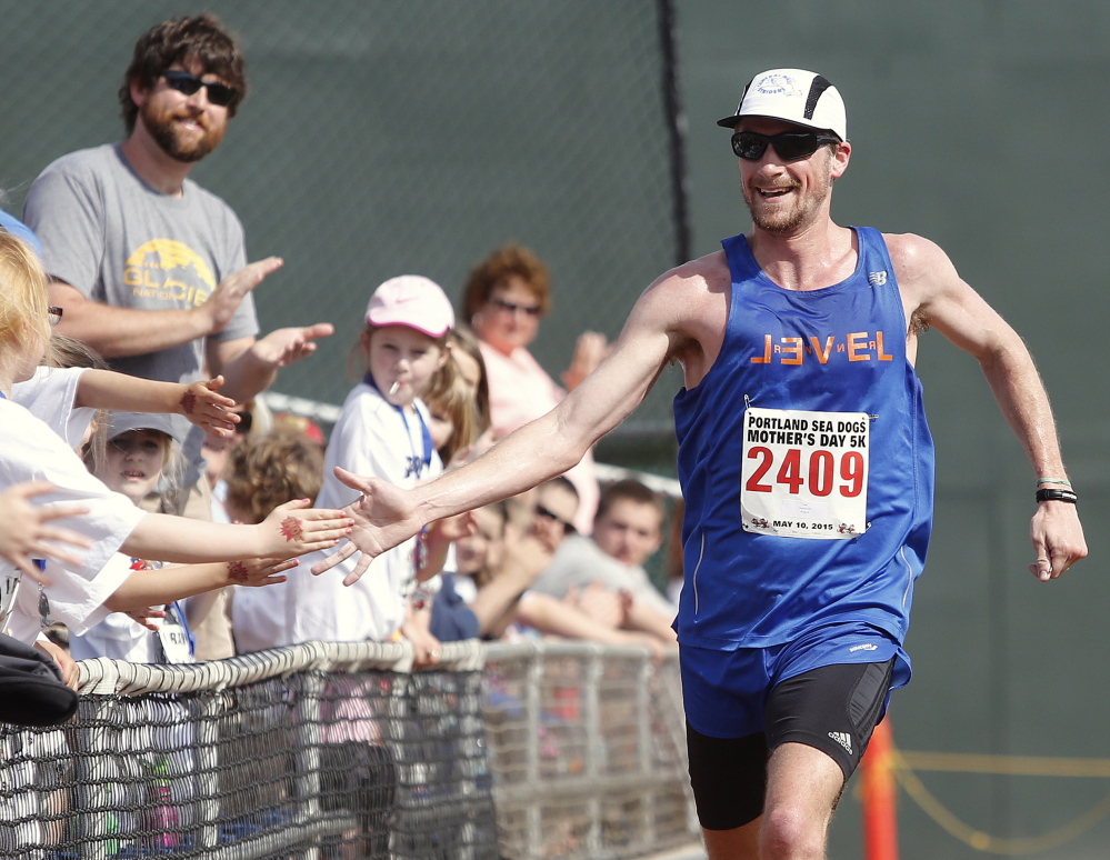 Derek Davis/Staff Photographer
Dan Vassallo, 30, of Peabody, Mass., greets fans as he finishes first overall in Sunday’s Portland Sea Dogs Mother’s Day 5K. The race ended at Hadlock Field.