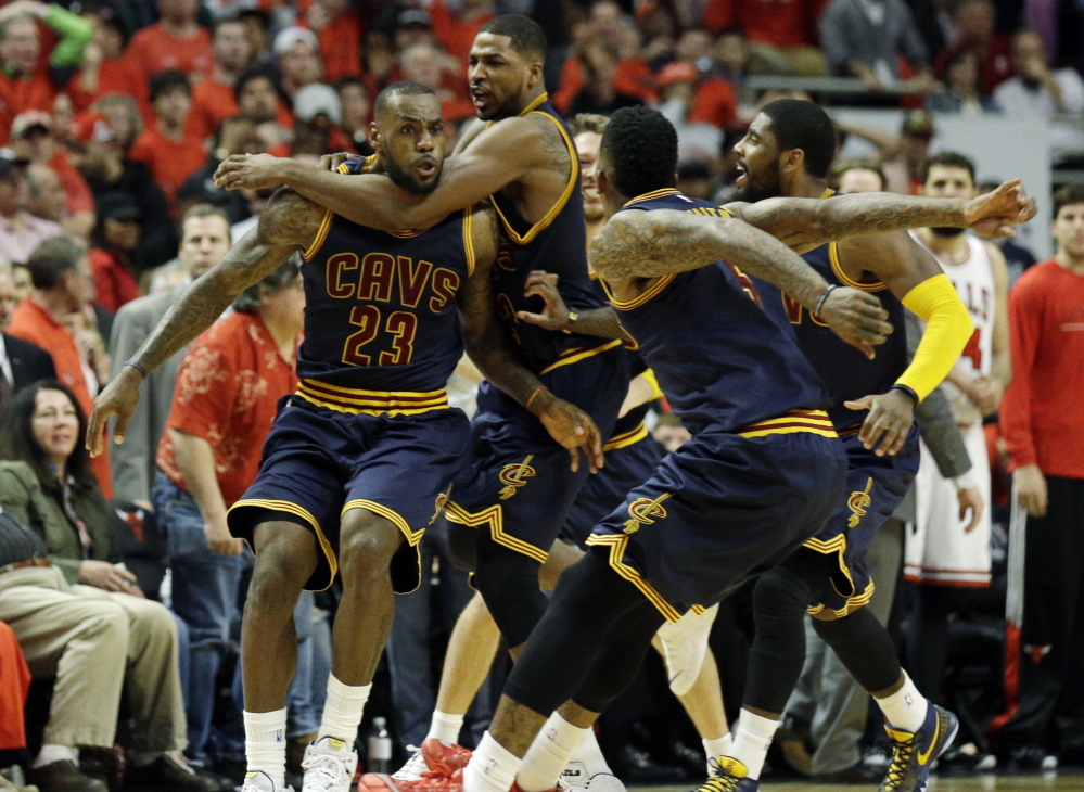 LeBron James, left, is mobbed by his teammates after his buzzer-beating jumper gave the Cleveland Cavaliers an 86-84 win Sunday over the Chicago Bulls, evening the best-of-seven series at two games apiece.