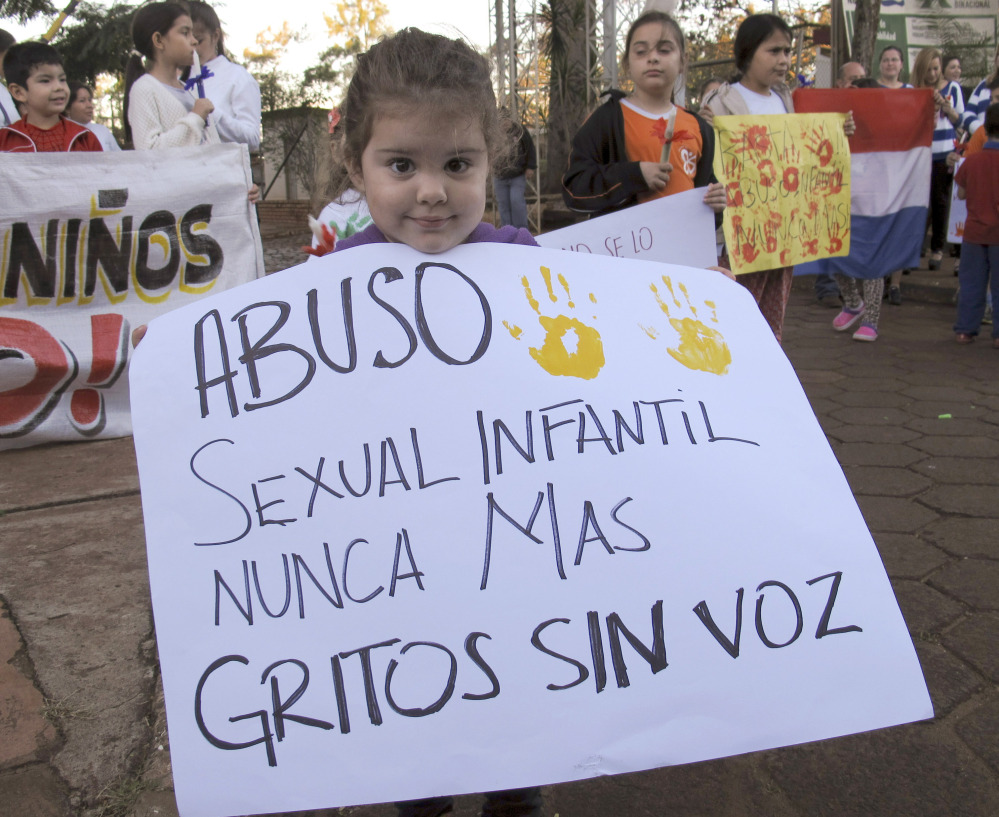 A child holds a sign that reads in Spanish “Sexual child abuse never again, screams without voice,” at a demonstration in Ciudad del Este, Paraguay, on Monday.