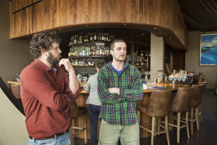 Andrew Taylor, left, and Mike Wiley, co-owners of Hugo’s, Eventide Oyster Co. and The Honey Paw with Arlin Smith, talk about their disagreement with food blogger John Golden in the dining area of Hugo’s on Monday.