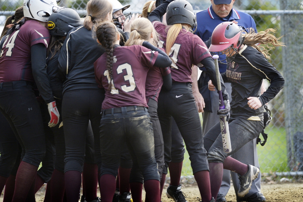 Brooke Cross, right, is greeted at home by her Thornton Academy teammates after hitting a three-run home run to tie the game in the seventh inning of the Trojans’ 11-9 win.
