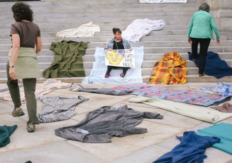 Joanie Klayman, left, and Caroline Fernandes, both of Preble Street, place blankets on the steps of Portland City Hall while Mary Jo Skofield from Homeless Voices for Justice holds a sign Tuesday in protest of potential budget cuts to homeless overflow housing.
Whitney Hayward/Staff Photographer
