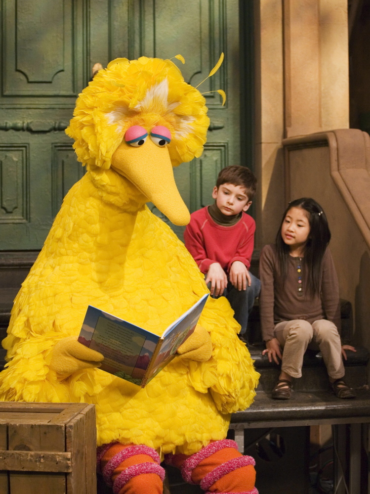 Big Bird, voiced by Caroll Spinney, reads to children during a 2008 taping of “Sesame Street.”