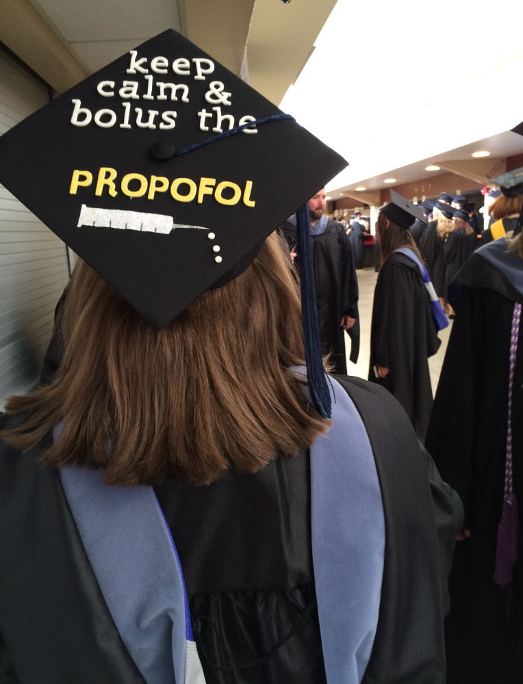 Brittney Painter makes a reference to her master of science in nurse anesthesia on her mortarboard as she waits to graduate at Cross Insurance Arena in Portland on Saturday. Painter was one of 1,449 graduates who received degrees at the University of New England’s 180th commencement ceremony.