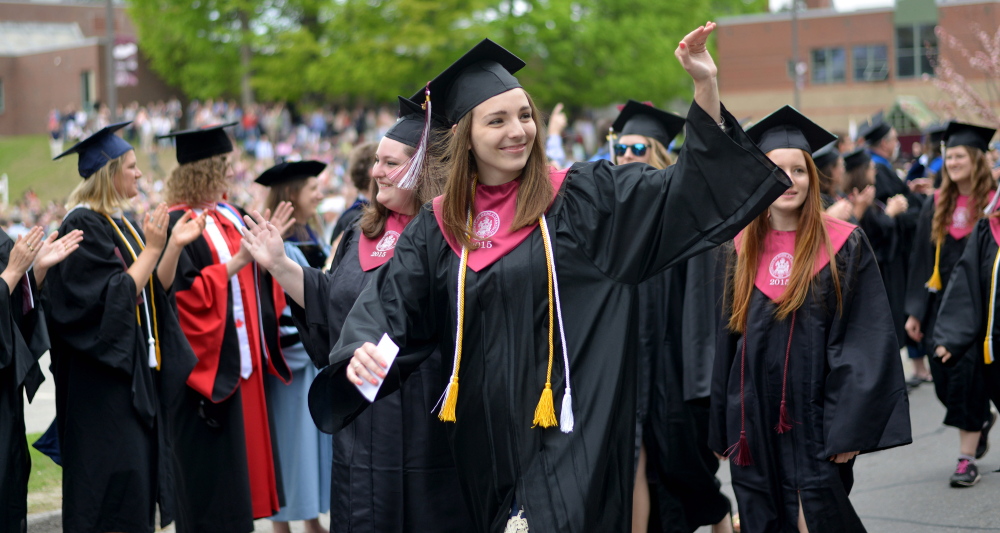 University of Maine at Farmington graduates wave to friends and family as they march down High Street during commencement ceremonies in Farmington on Saturday.
